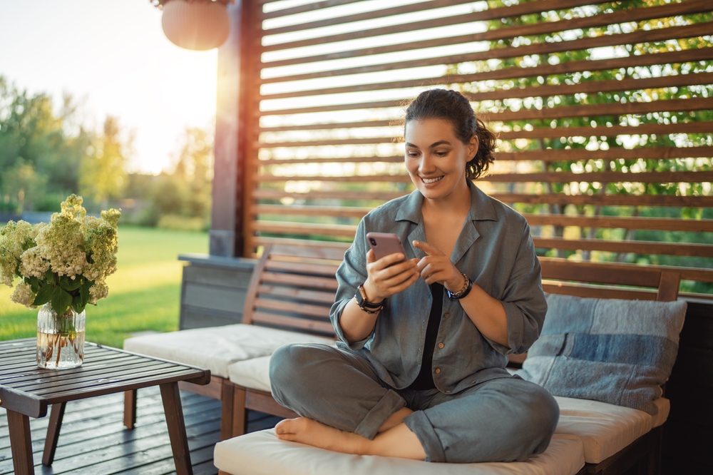 happy,young,woman,is,using,a,phone,sitting,on,the